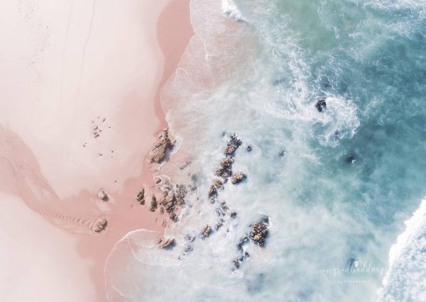 Aerial beach photograph of a beach with pink sand and light blue sea