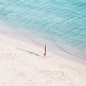 Handstand on Beach: aerial photograph of woman practicing handstand on the beach